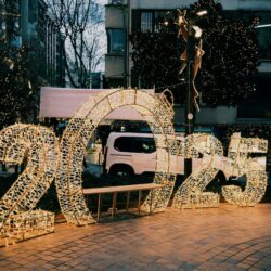 Illuminated 2025 sign on city street with decorative lights creating a festive atmosphere.